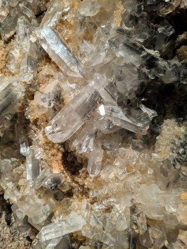 Clear quartz crystals embedded in a rough, textured rock surface.